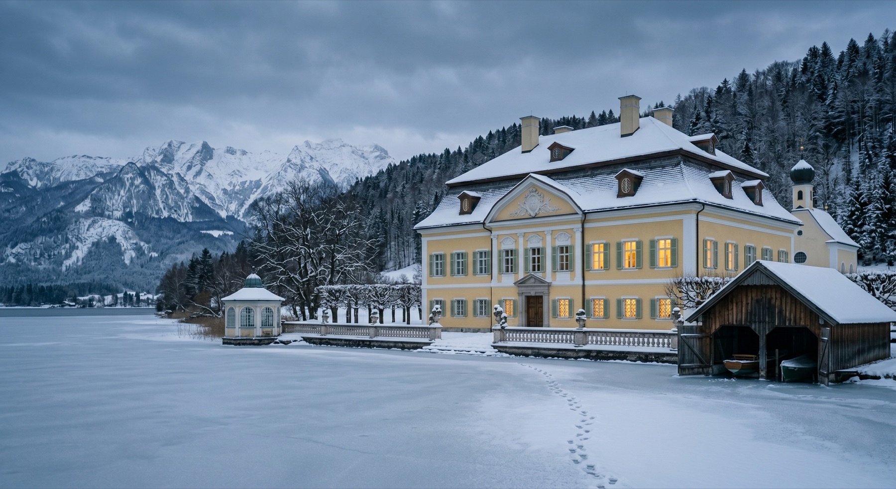 The schloss in winter, frozen lake in foreground, snow on the mansard roof, lit windows at dusk under grey alpine clouds.